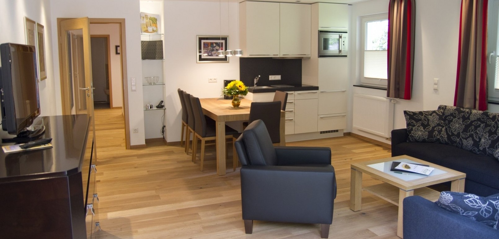 De woon-/eetkamer met kitchenette in de vakantiewoning “Auf der Tenne” in het Schneisberghaus van Hotel Jagdhaus Wiese in het Sauerland is licht en modern ingericht.