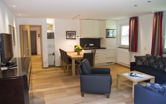 The living/dining room with kitchenette in the ‘Auf der Tenne’ holiday flat in the Schneisberghaus belonging to the Hotel Jagdhaus Wiese in the Sauerland is bright and modernly furnished.