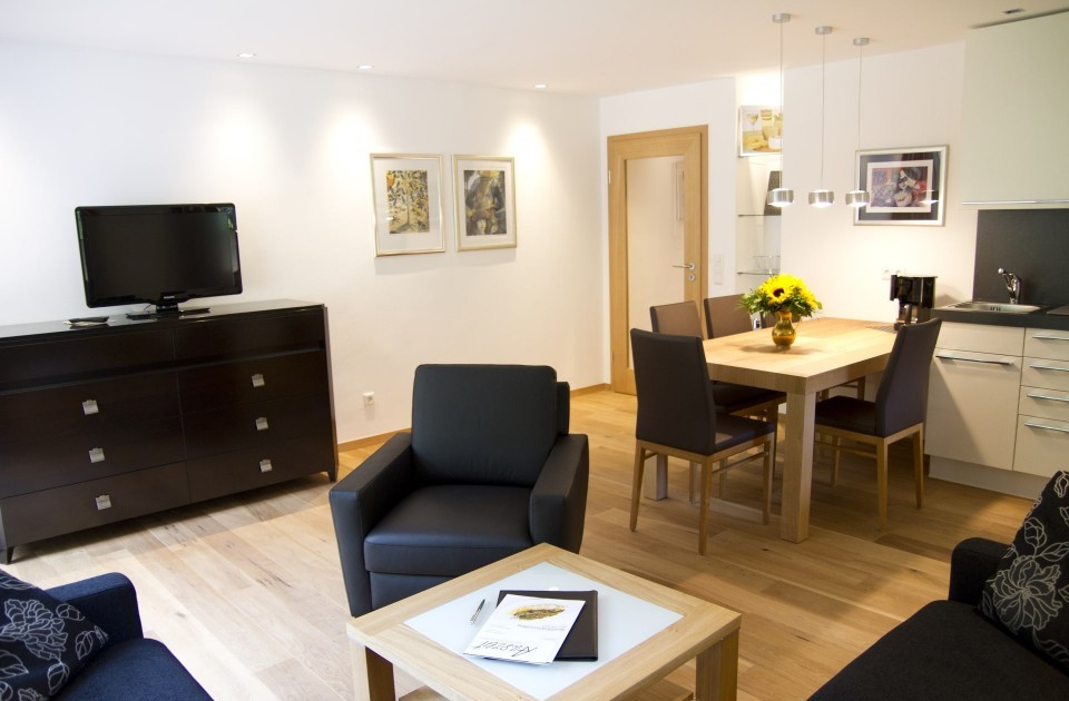 Das Wohnzimmer mit Küchenzeile in der Ferienwohnung "Auf der Tenne" im zum Hotel Jagdhaus Wiese im Sauerland gehörenden Schneisberghaus ist hell und modern eingerichtet.