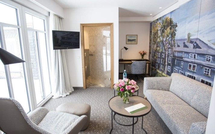 Cosy living room with sitting area and desk in a modern junior suite Classic at the Hotel Jagdhaus Wiese in the Sauerland