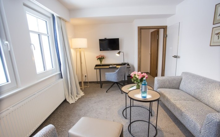 Cosy living room with sitting area and desk in a modern Classic Suite at the Hotel Jagdhaus Wiese in the Sauerland